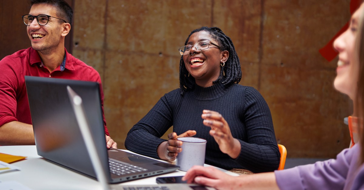 Coworkers smiling around a laptop